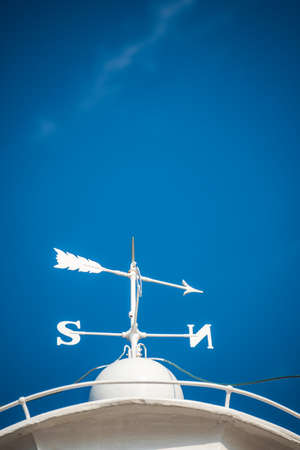 Lighthouse dome marked with the directions of the world. White arrows in the blue sky designating the north, south, east and west.の写真素材