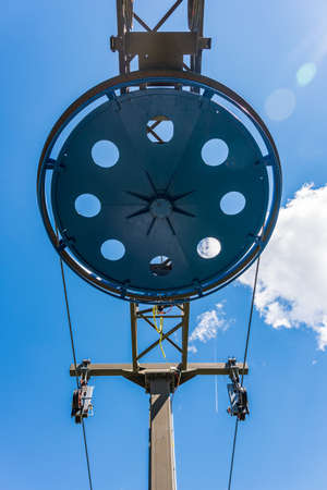 Fragment of the ski lift. Elements of the steel structure, wheel, steel ropes, tensions, sensors, electric wires on the background of the blue sky.の写真素材
