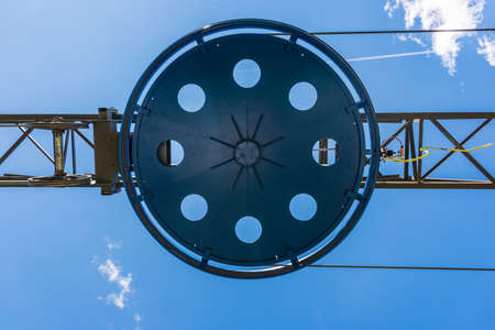 Fragment of the ski lift. Elements of the steel structure, wheel, steel ropes, tensions, sensors, electric wires on the background of the blue sky.の写真素材