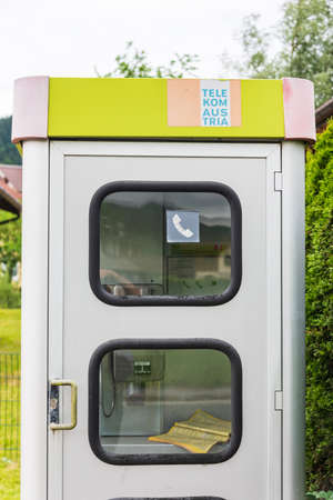 Gray and yellow telephone booth Austria Telekom with a telephone book visible inside. Flachau, Austria, Europe - June 30 2021のeditorial素材