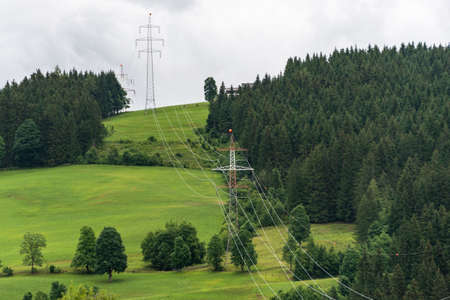 High voltage overhead power line, power pylon, steel lattice tower standing in the mountains landscape. Electricity distribution system in Europeの写真素材