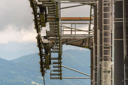 The details of a new ski lift, cable way. Support pole, rope, wheels, steps, steel construction. In the background panorama of the mountains.の写真素材
