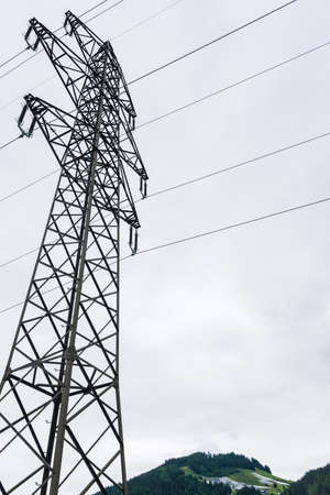 High voltage overhead power line, power pylon, steel lattice tower standing in the Alps mountains...
