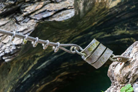 Stainless steel rope and bow rope clamps stretched between the rocks.の写真素材