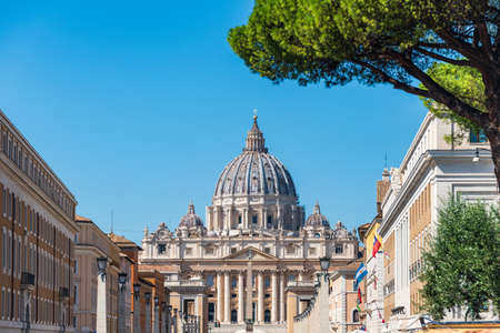 The dome of Saint Peter's Basilica and its statues of saints at St. Peter's Square, Vatican City view from Via della Conciliazione in Rome, Italy. Pine tree at the foreground.のeditorial素材