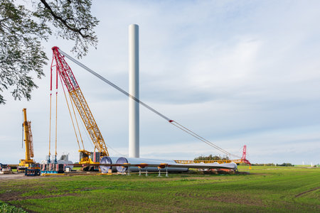 Construction site prepared for the assembly of a wind farm. Visible car crane, yellow crane and a folded gondola, mast the rotor and rotor blades all around. Rogozno, Poland - 10.18.2021のeditorial素材