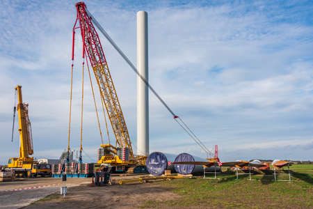 Construction site prepared for the assembly of a wind farm. Visible car crane, yellow crane and a folded gondola, mast the rotor and rotor blades all around. Rogozno, Poland - 10.18.2021のeditorial素材