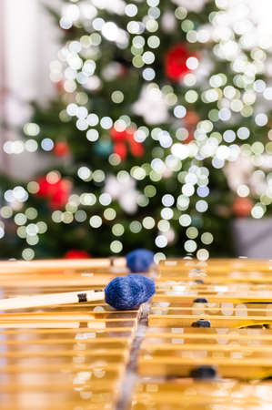 Vibraphone sticks lying on this percussion instrument. In the background, blurry, out-of-focus lights of the Christmas tree.の写真素材