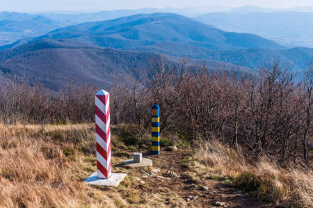 Border markes on a Polish-Ukraine boundary. The Polish eastern border, is also the border of the European Union and NATO. In the background, the blue sky and trees, bushes and grass of Bieszczady Mountains National Park, Polandの写真素材