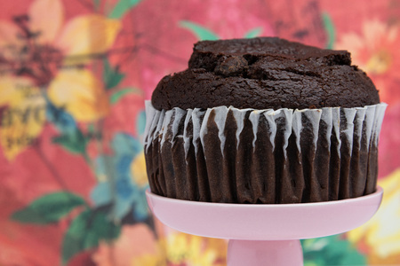 a chocolate muffin on a pink dessert stand pedestal against a  fun background in a dessert shop.の写真素材