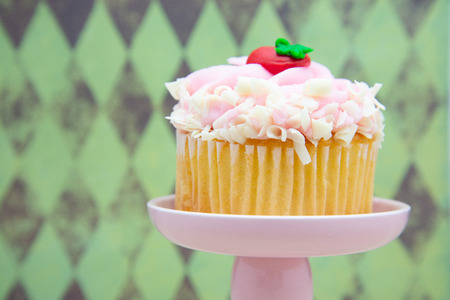 strawberry cupcake with pink frosting on a dessert display stand pillar pedestal.の写真素材