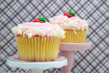 strawberry cupcake with pink frosting on a dessert display stand pillar pedestal. pair of cupcakes. two cupcakes.の写真素材