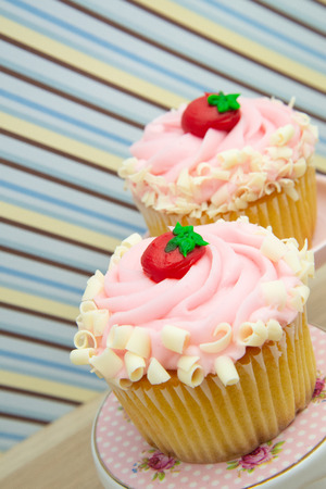 strawberry cupcake with pink frosting on a dessert display stand pillar pedestal. pair of cupcakes. two cupcakes.の写真素材
