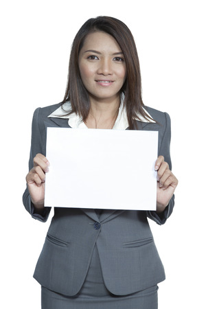 Happy smiling young pretty attractive brunette Asian business woman standing positive showing blank signboard, isolated on white backgroundの写真素材