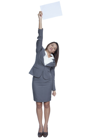 Full length happy smiling young pretty attractive brunette Asian business woman standing positive showing blank signboard, isolated on white backgroundの写真素材