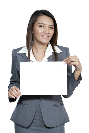 Happy smiling young pretty attractive brunette Asian business woman standing positive showing blank signboard, isolated on white backgroundの写真素材