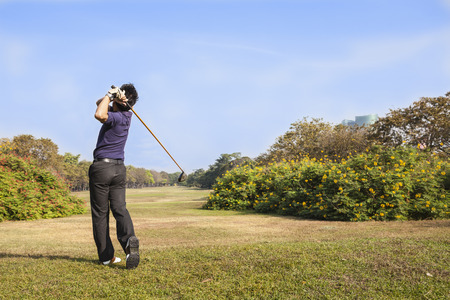Male golf player teeing off golf ball from tee box, wonderful cloud formation in background の写真素材
