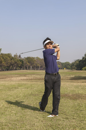 Golfer swinging his club in green grass on a sunny summer dayの写真素材