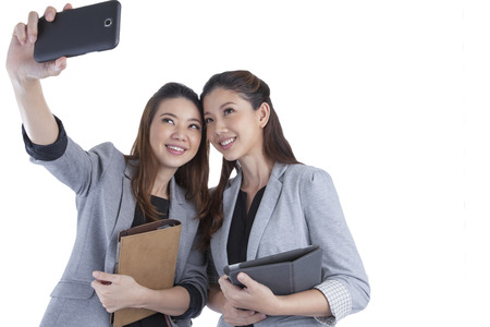 Young businesswomen taking self portrait on white backgroundの写真素材