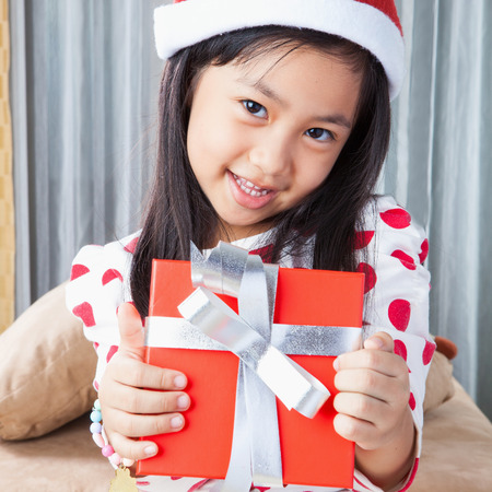 Happy small girl in Santa hat with present have a Christmasの写真素材