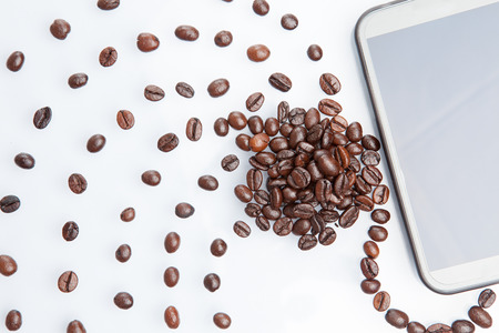 Heap of coffee beans with a mobile phone. isolated on white background.