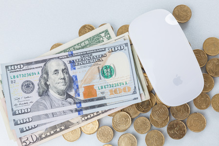Computer mouse on dollars and Euro coins isolated on white