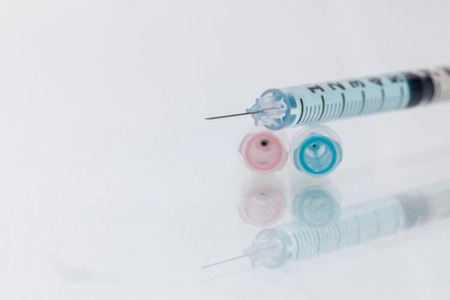 Medical syringe with blue solution close-up isolated on a white background. and Close-up of medical syringe with drugの写真素材