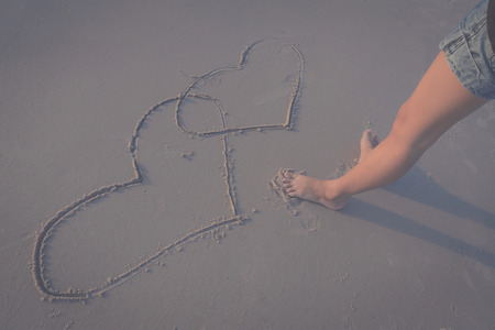 woman drawing a heart in the sand on a tropical beachの写真素材
