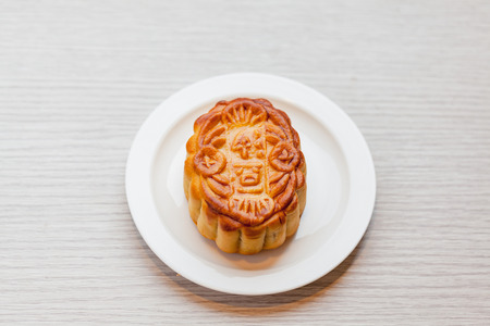 Chiness moon cake with white plate on the wooden table / 2 Chiness capital letters are wish and not...