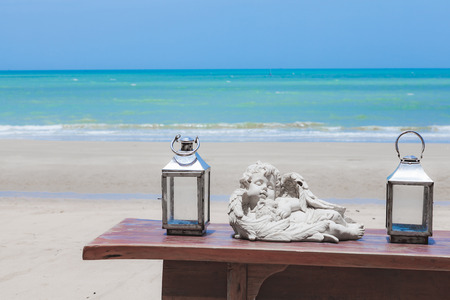 wooden table with silver colour decoration lamp or lantern with white candle inside by the sea on...