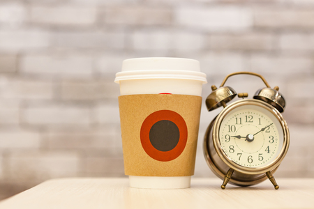 Coffee morning with Retro alarm clock on table on office backgroundの写真素材