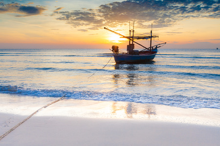 An impressive sunrise over the sea with boats at Hua Hin beach, Thailand.の写真素材