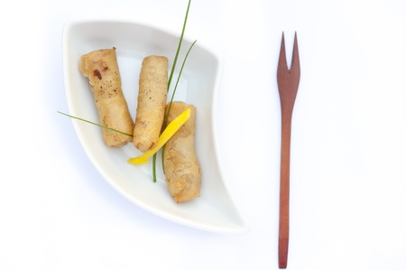 Three egg rolls with a wood fork in a white bowlの写真素材
