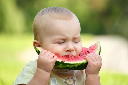 little baby eating watermelon outdoorsの写真素材