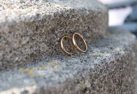Golden wedding rings on stone outdoorsの写真素材