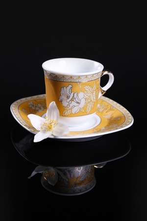 yellow cup on black with jasmine flowerの写真素材