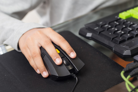 Close up on right hand for clicking over mouse by gamer kid