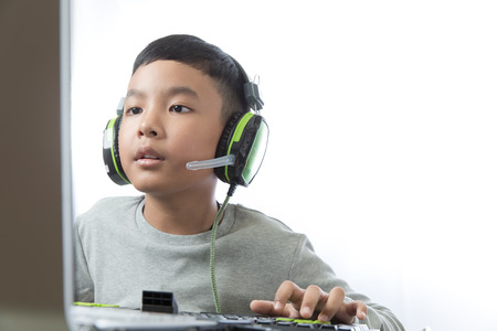 Asian kid play computer internet games and wear headset to communicate