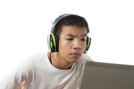 Asian teenager using computer and listen to music with doubt on his face