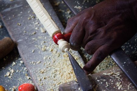Artisan engaged in turning and painting wooden rod at Madhu Vana near Bengaluru, Karnataka, India,...