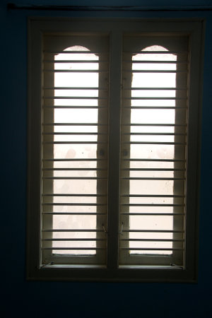 View of window with bar protectors and two glass window shutters