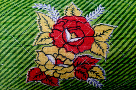 Closer view of printed red and yellow flowers and leaves with green, diagonal, striped patten in...