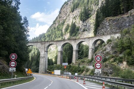 A road and an old train bridge in Chamonix, France. Perfect moment in alpine highlands. Mont-Blanc massif.の写真素材