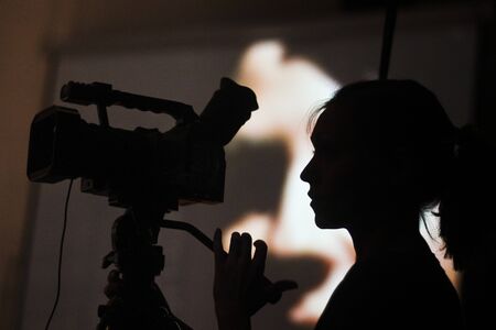 A silhouette of videographer young woman with a video cameraの写真素材
