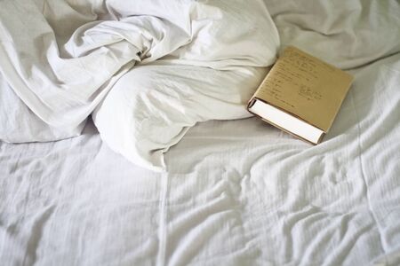 Spend a day reading a book in bed with white blanketの写真素材