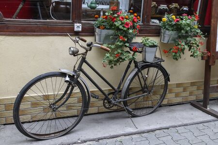 Old black bike near the cosy cafe with red and orange flowersの写真素材