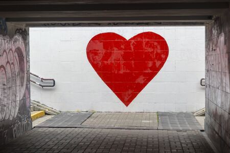 A big red heart is painted on a white wall. Street graffiti, street art expressing loveの写真素材