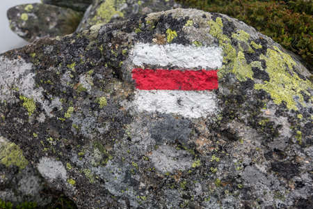 Tourist route mark on stone, painted in white and red guiding the way to the hiking mountainの写真素材