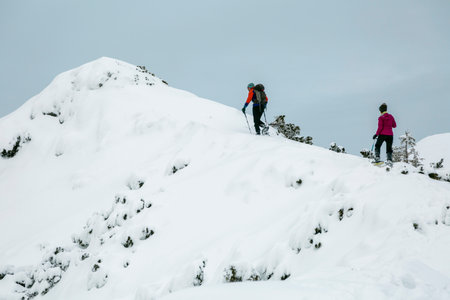 Two hikers alpinists climbing up the snowy mountain on Sunset. Alpine winter view. Carpathians, Marmarosyのeditorial素材