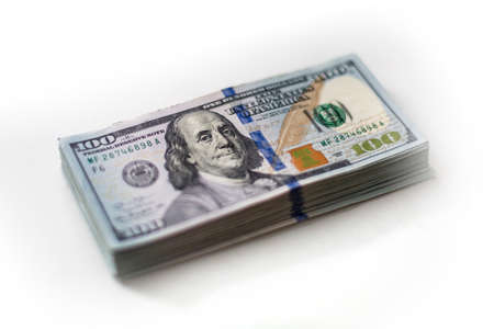 A pack of hundreds US dollars on white background: 100 usd currency banknotes. Inflation, business,...